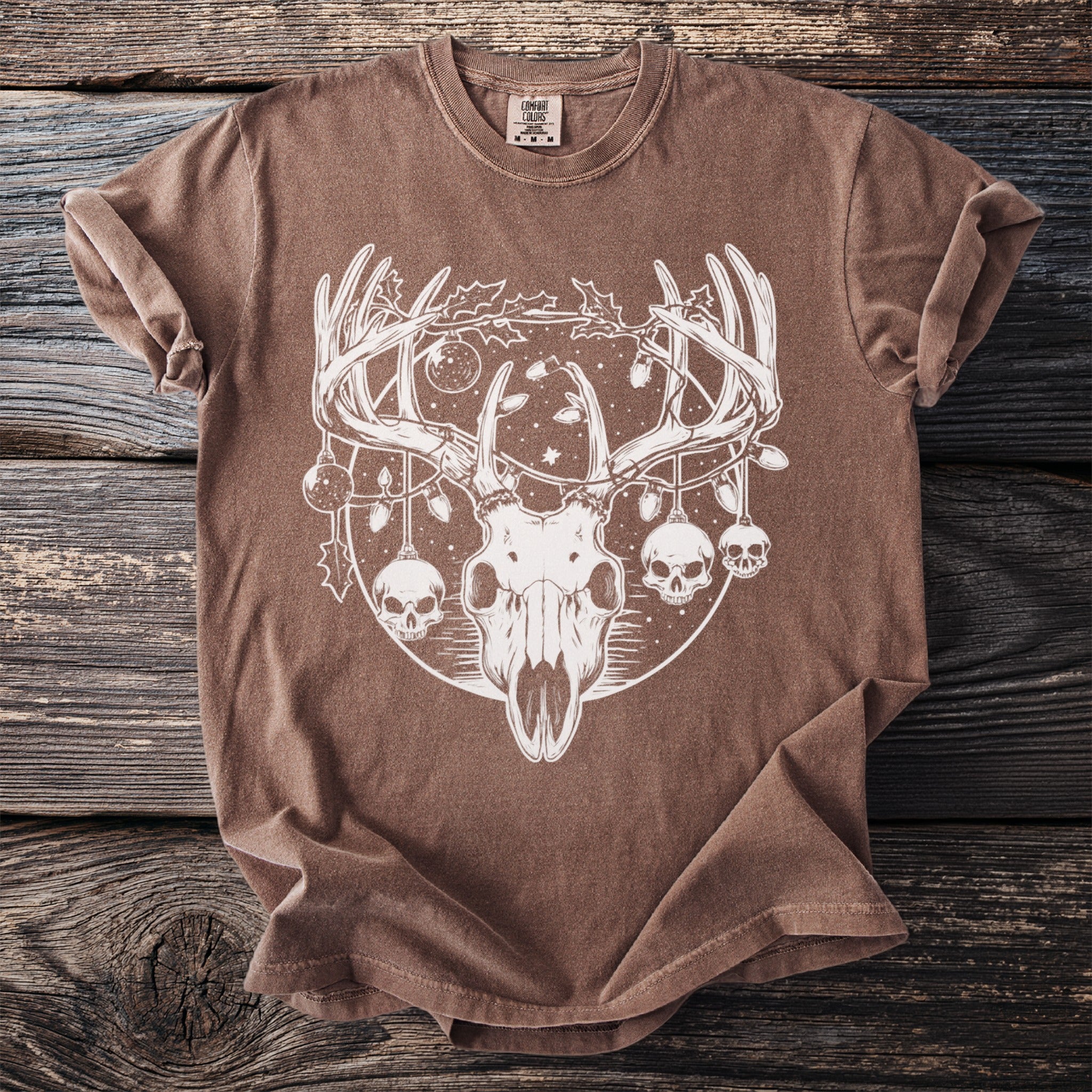 Brown t-shirt with white deer skull graphic featuring ornaments and skulls.