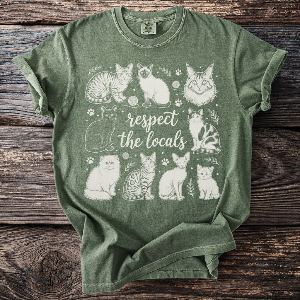 Green t-shirt with "respect the locals" text and various cat illustrations.