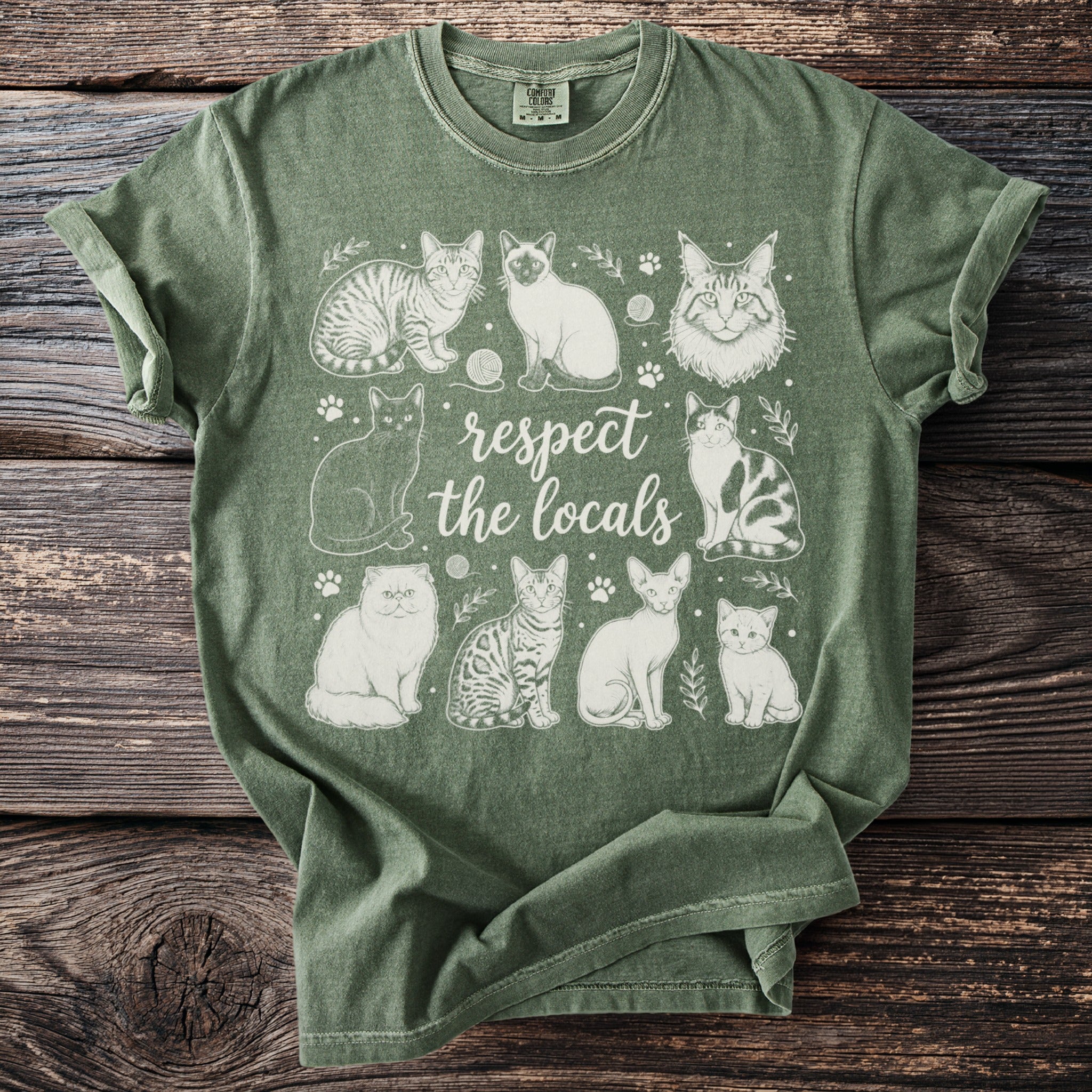 Green t-shirt with "respect the locals" text and various cat illustrations.