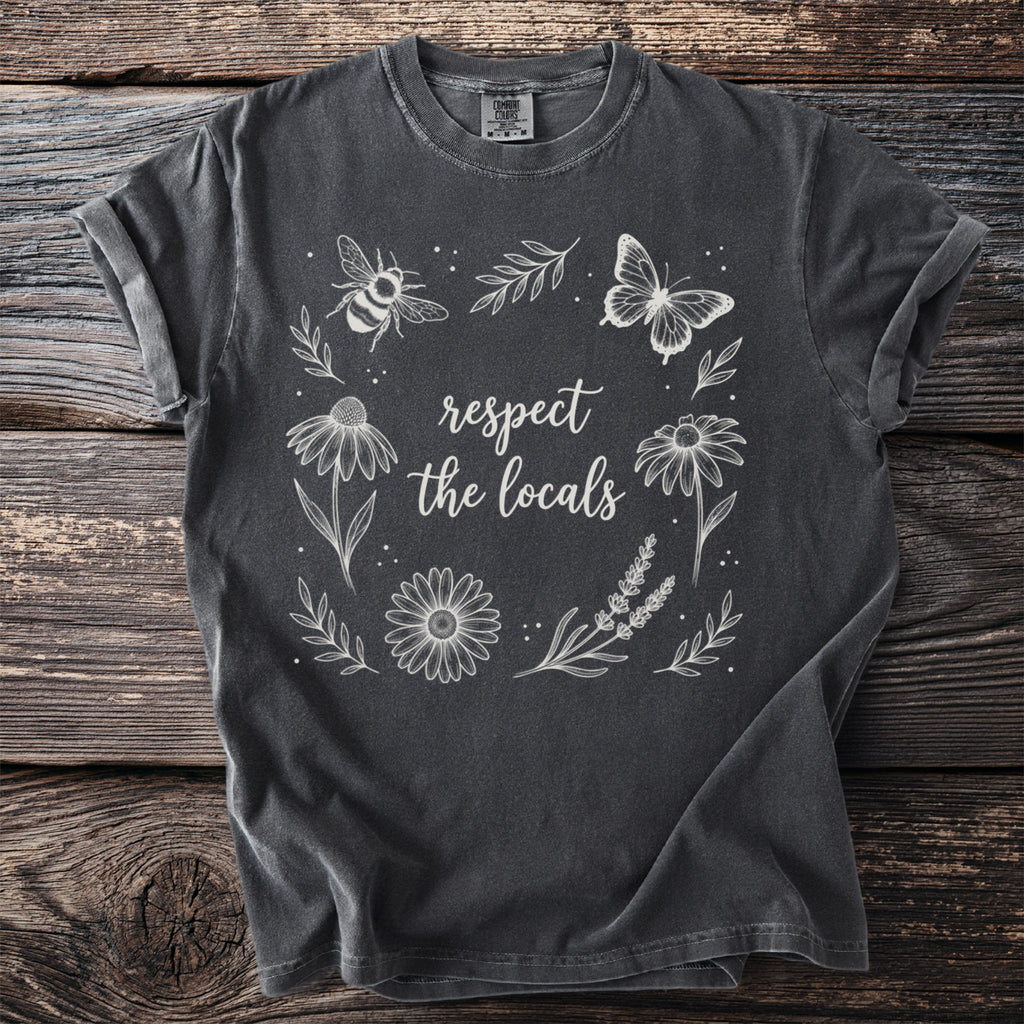 Dark grey t-shirt with white outline art of flowers, bee, butterfly, and text.