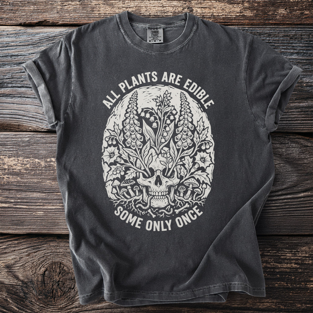 Dark grey t-shirt with skull, plants, and text: "ALL PLANTS ARE EDIBLE SOME ONLY ONCE."