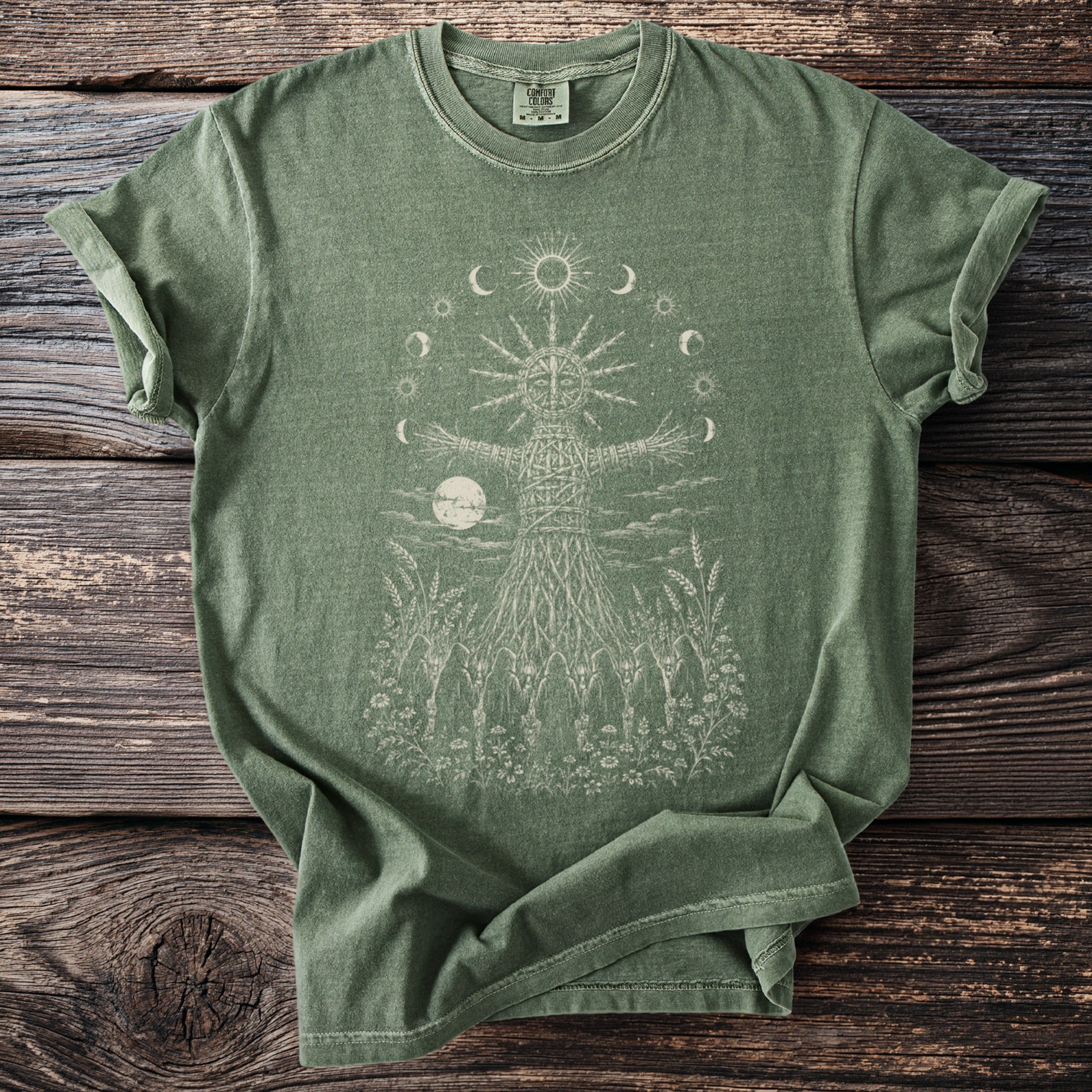 Green t-shirt with a woven figure, moon, and celestial bodies graphic.