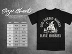 Black t-shirt with "God forbid women have hobbies" graphic and size chart.