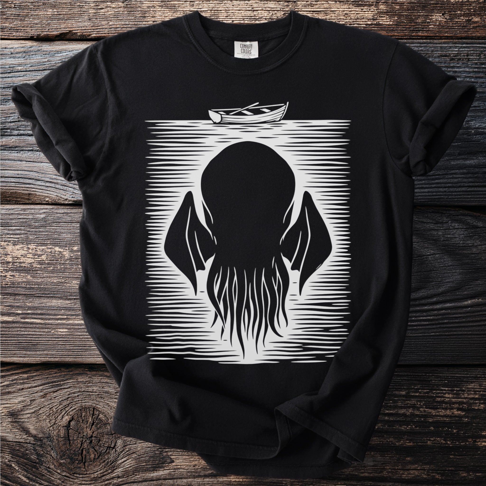 Black t-shirt with a stylized graphic of a monster's head and tentacles with a boat above.