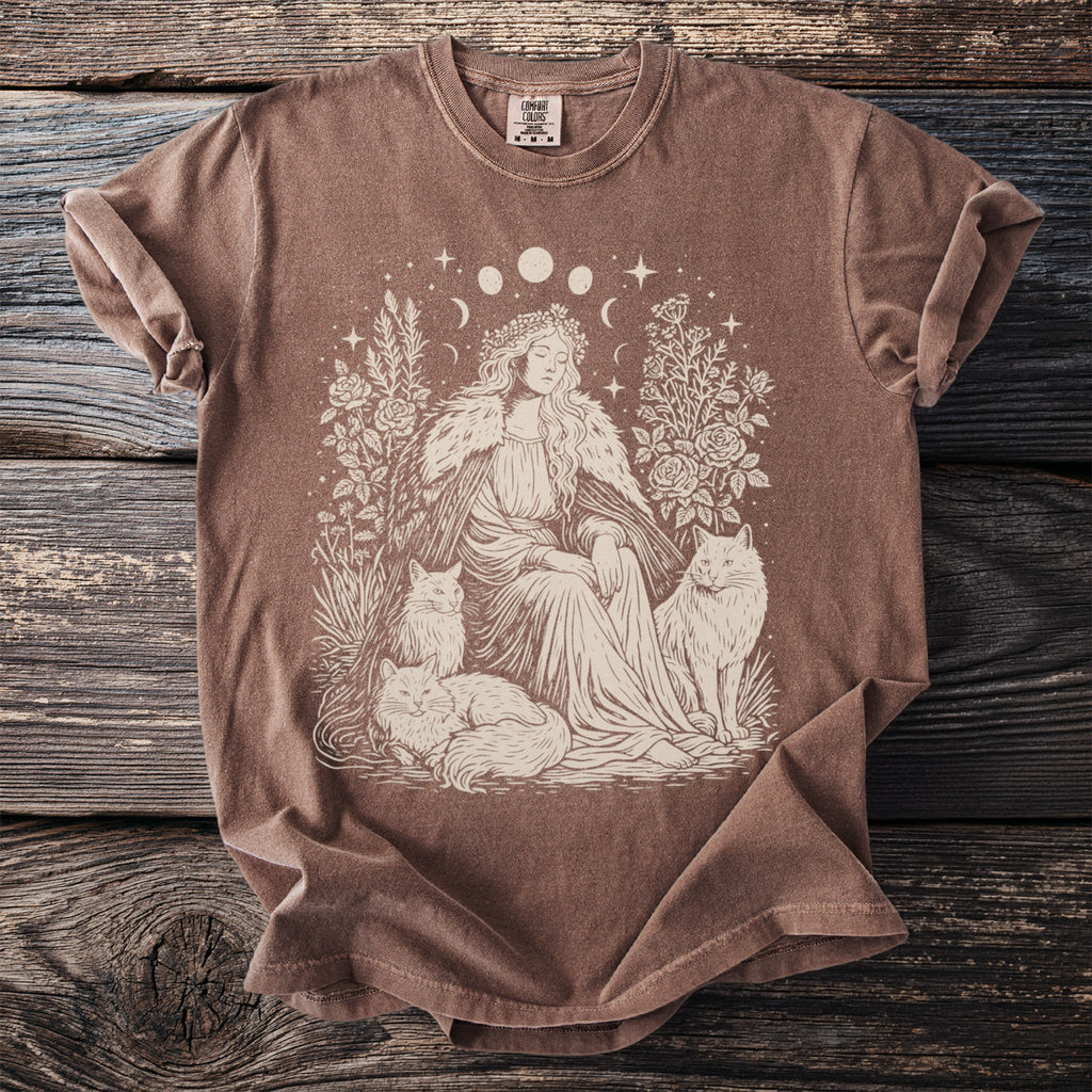 Brown t-shirt with illustration of woman in flower crown, cats, and moon phases.
