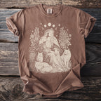 Brown t-shirt with illustration of woman in flower crown, cats, and moon phases.