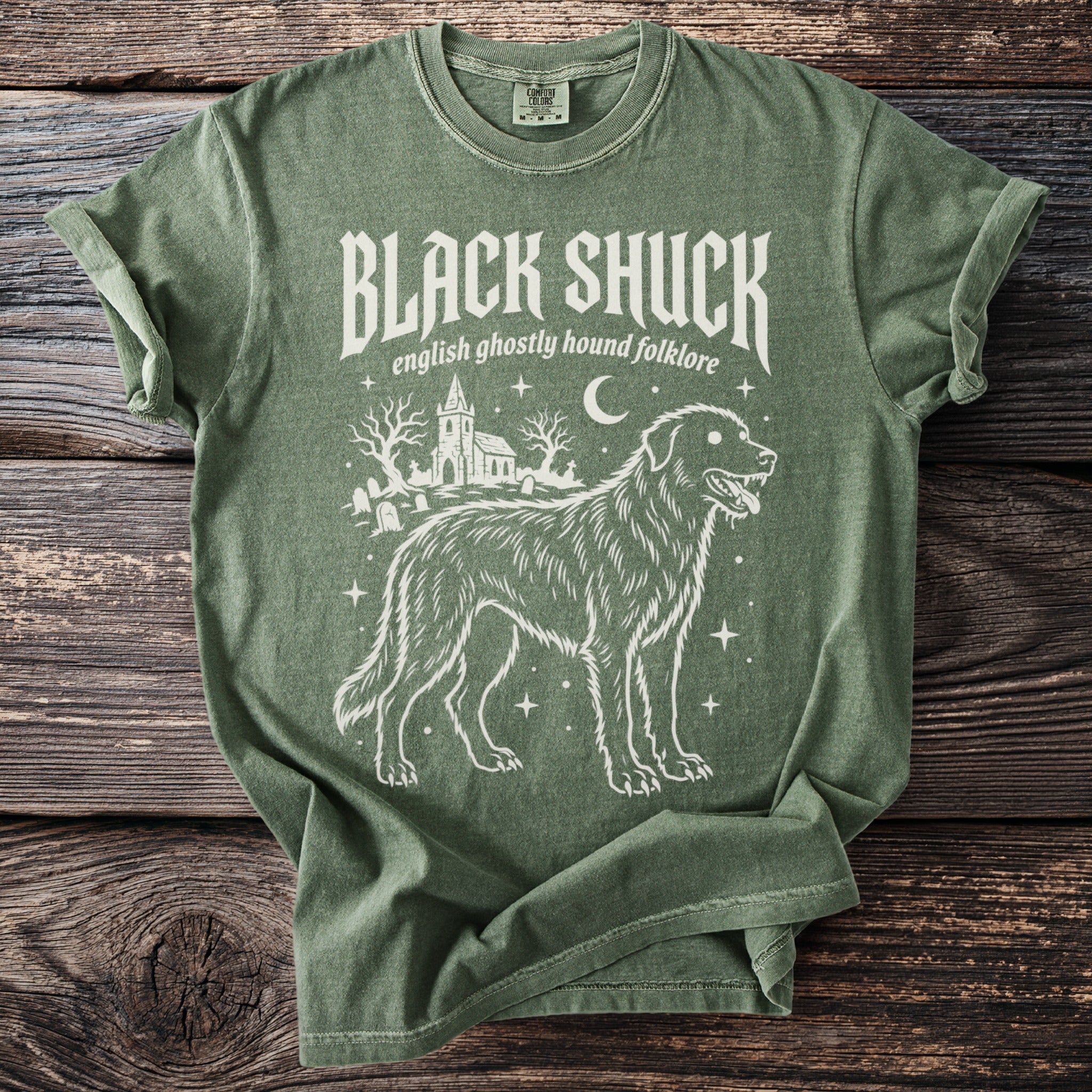 Green t-shirt with "BLACK SHUCK english ghostly hound folklore" and dog illustration.