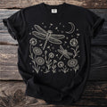 Black t-shirt with line art of dragonflies, flowers, dandelions, moon, and stars.