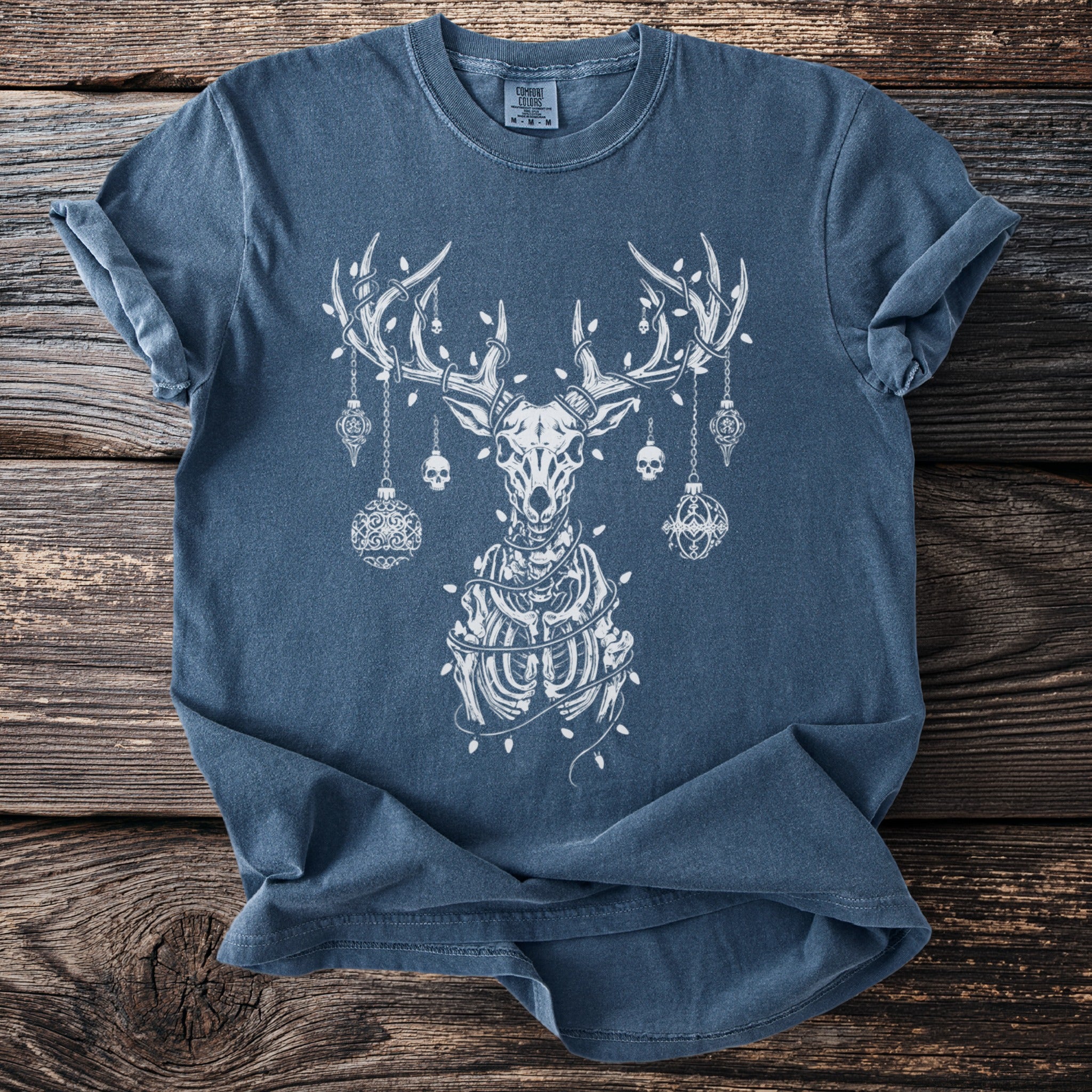 Blue t-shirt with white print of a skeletal deer with ornaments and lights.