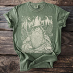 Green t-shirt with a graphic print of a wizard, wolves, and eagles in a forest.