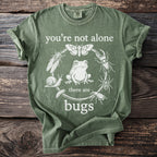 Green t-shirt with "you're not alone there are bugs" text and insect illustrations.