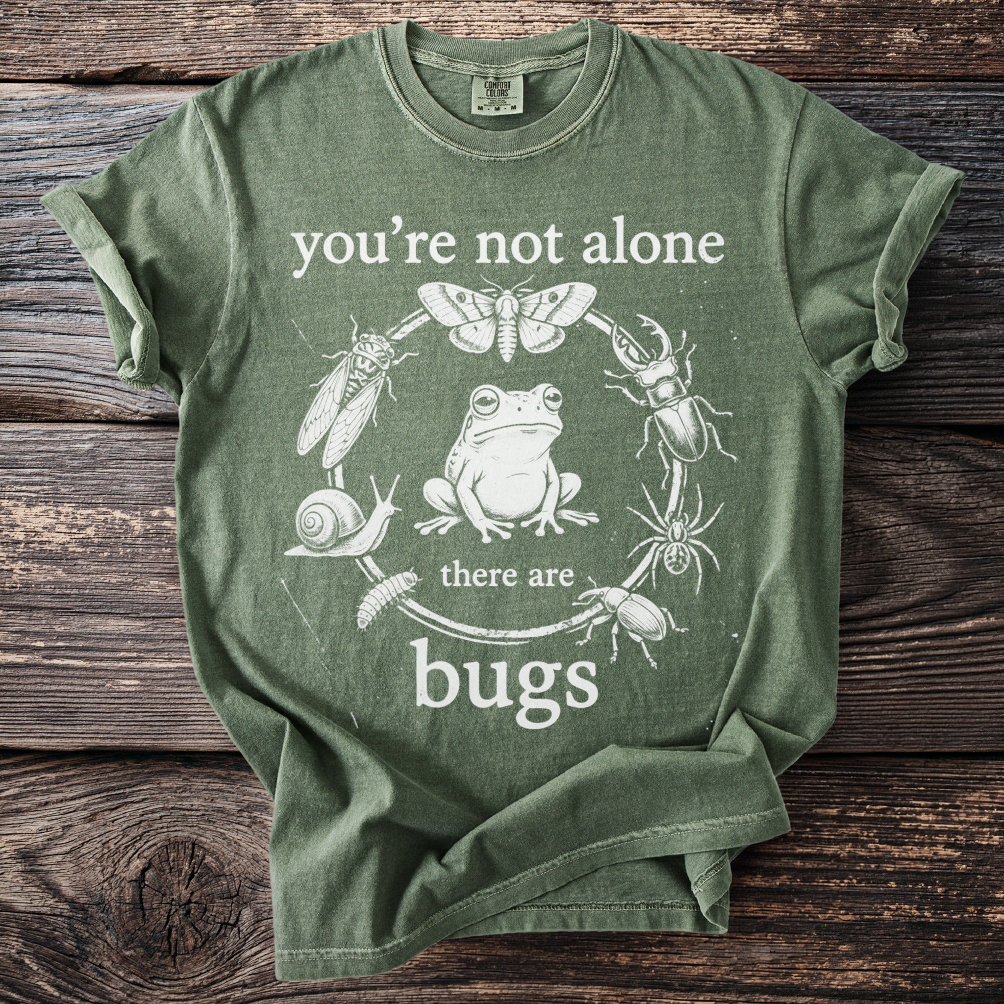 Green t-shirt with "you're not alone there are bugs" text and insect illustrations.