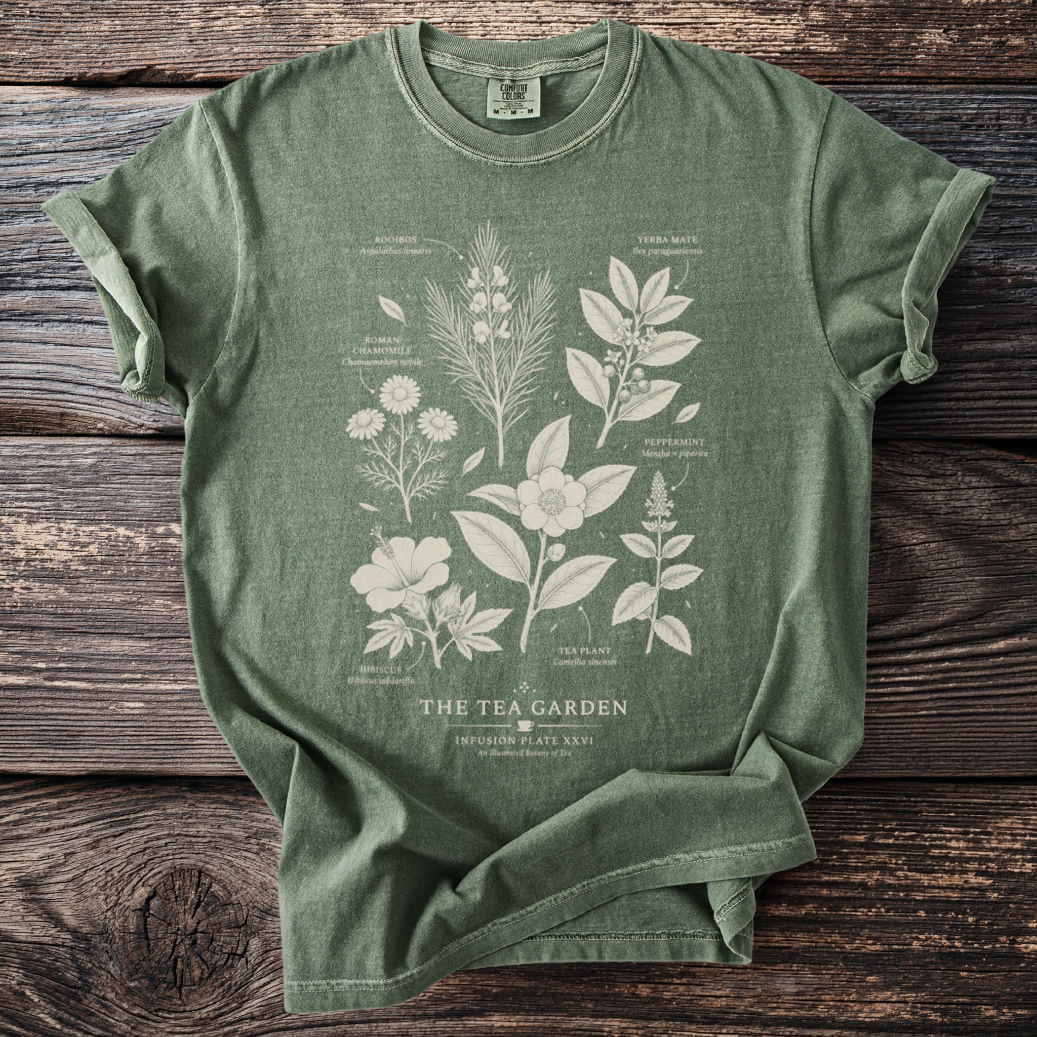 Green t-shirt with "The Tea Garden" graphic of botanical tea ingredients.