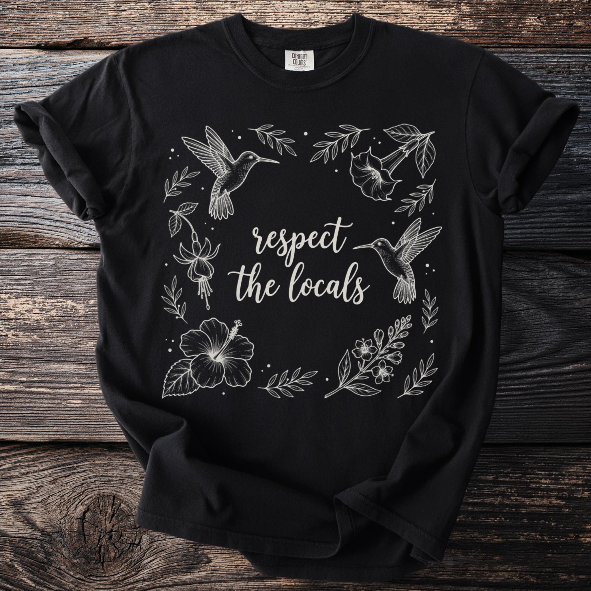 Black t-shirt with "respect the locals" text surrounded by hummingbirds and flowers.