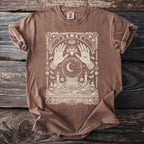 Brown t-shirt with cream-colored mystical graphic featuring hands, crystal ball, moon, and celestial elements.