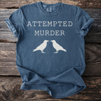 Blue t-shirt with "ATTEMPTED MURDER" text and two white ravens.