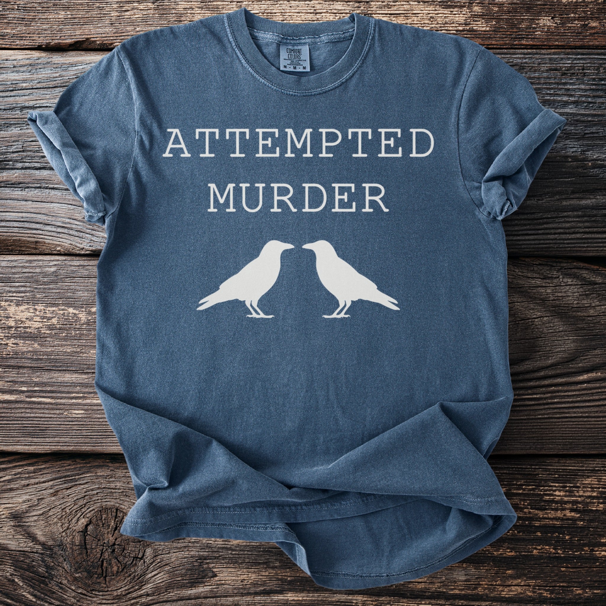 Blue t-shirt with "ATTEMPTED MURDER" text and two white ravens.
