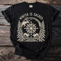 Black t-shirt with "WINTER IS SACRED" above a stag, two hares, pines and a snowflake.