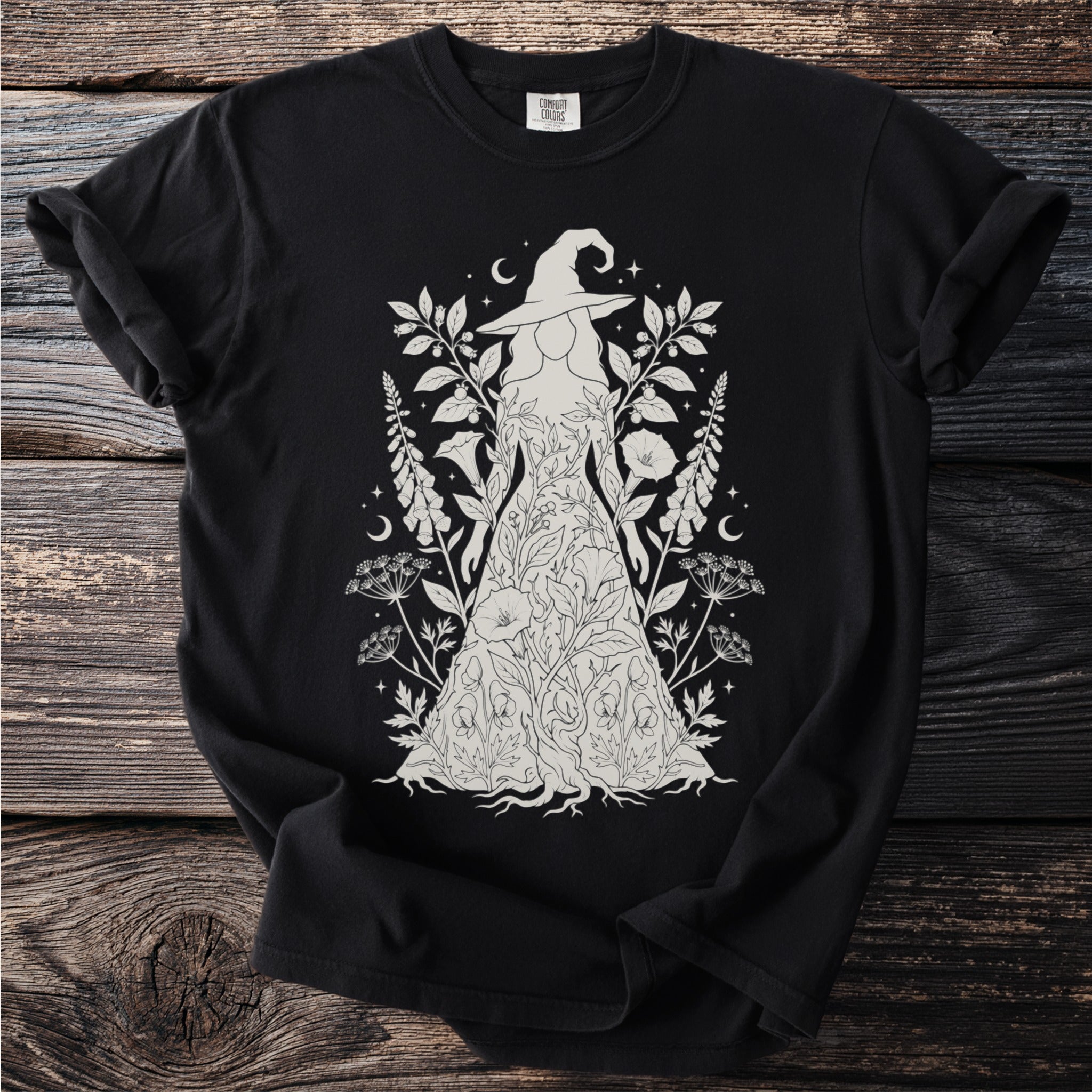 Black t-shirt with a line art design of a witch surrounded by foliage and celestial elements.