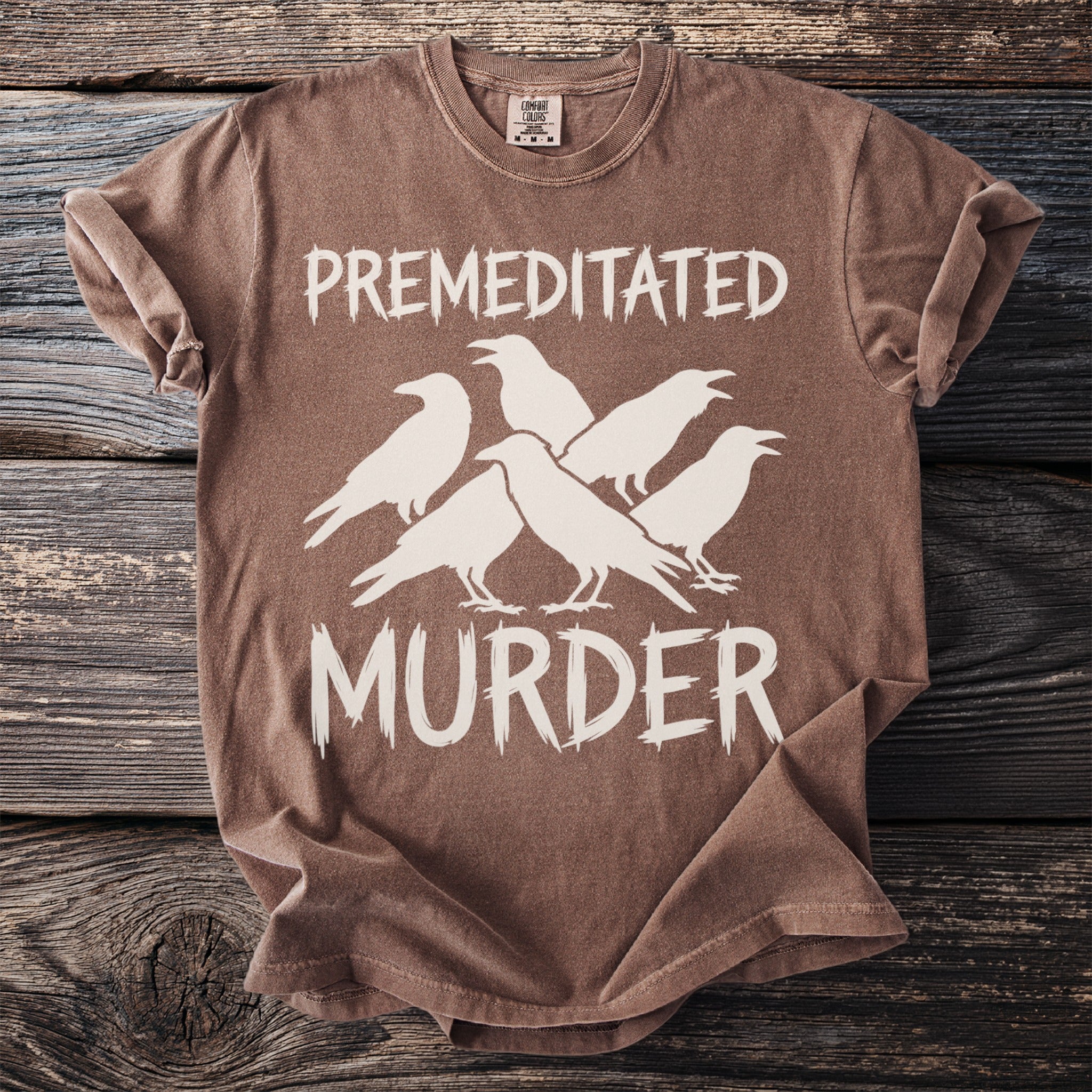 Brown t-shirt with white text reading "PREMEDITATED MURDER" and five white crow silhouettes.