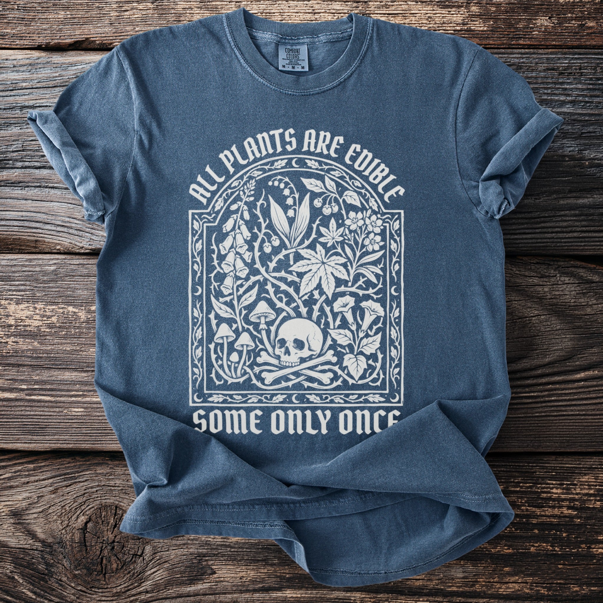 Blue t-shirt with white text and skull with bones illustration.
