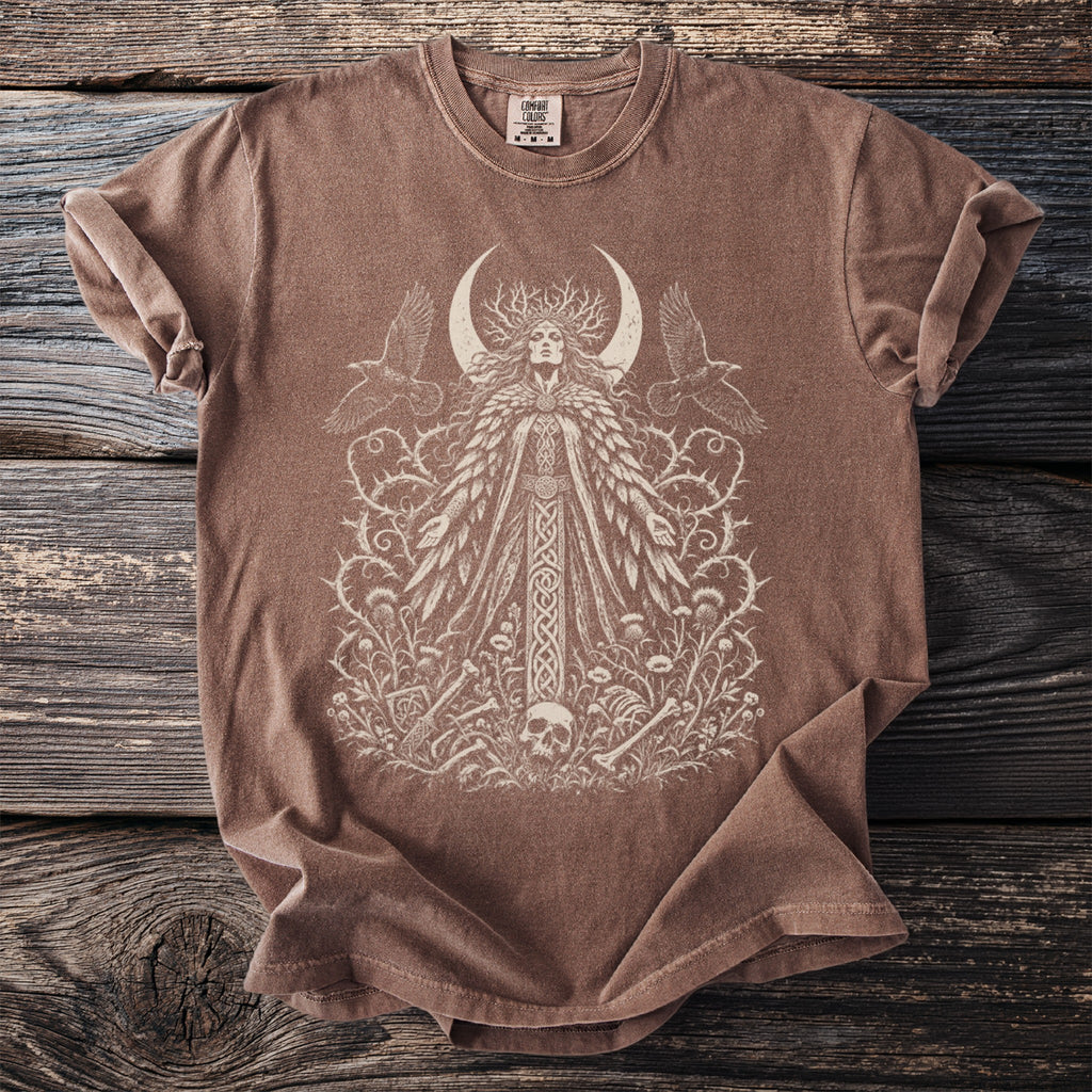 Brown t-shirt with a white graphic of a woman, crescent moon, ravens, and floral elements.