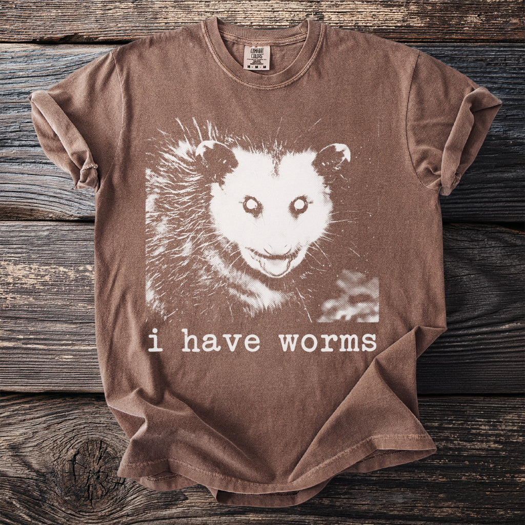 Brown t-shirt with white opossum graphic and text "i have worms".