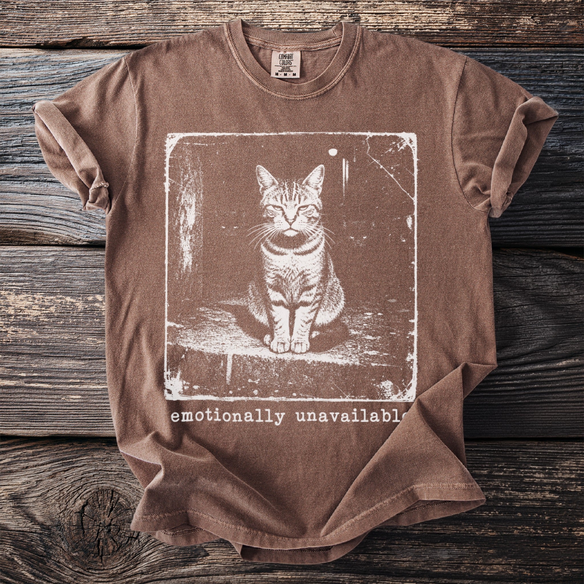 Brown t-shirt with white graphic of a cat and text "emotionally unavailable".