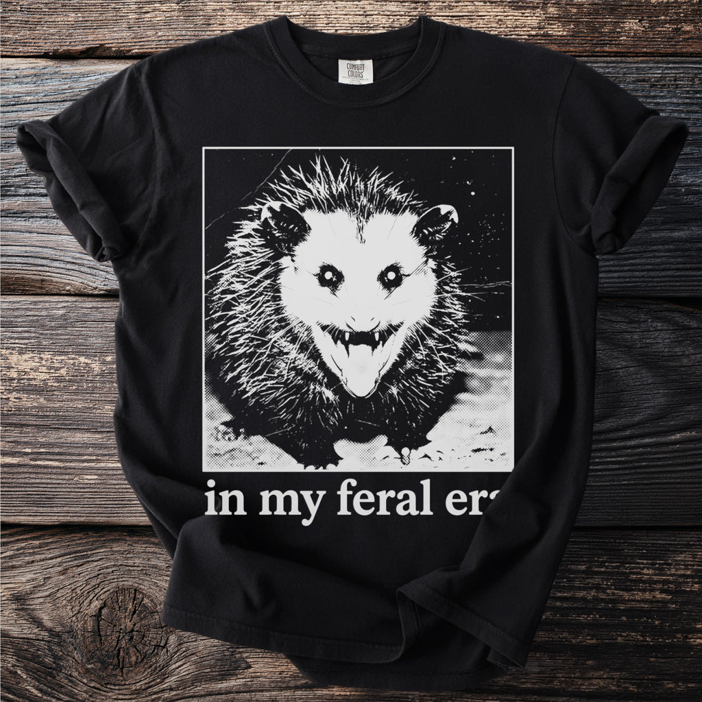 Black t-shirt with a graphic of a feral opossum and text "in my feral er".