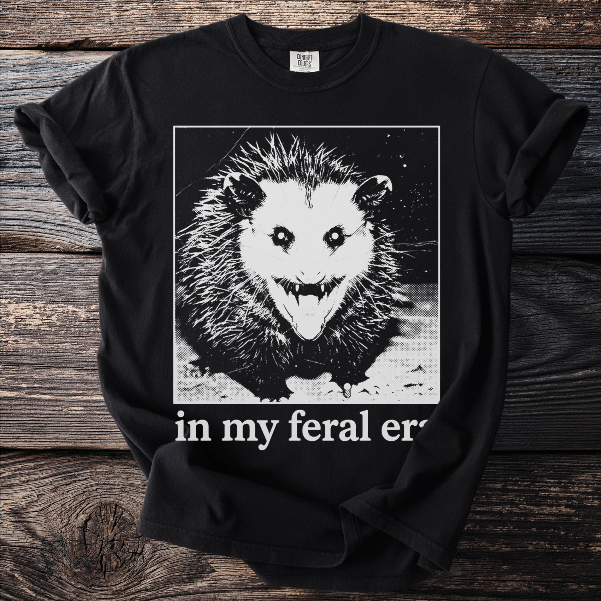 Black t-shirt with a graphic of a feral opossum and text "in my feral er".