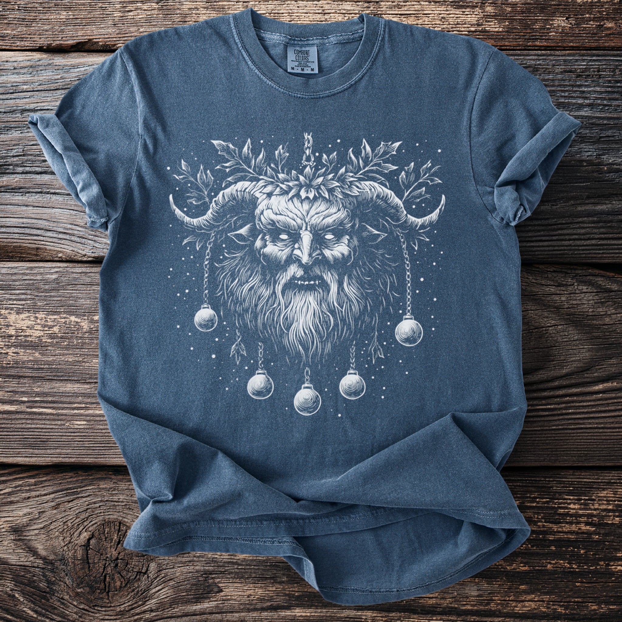Blue shirt with white illustration of a horned demon with a wreath and hanging ornaments.