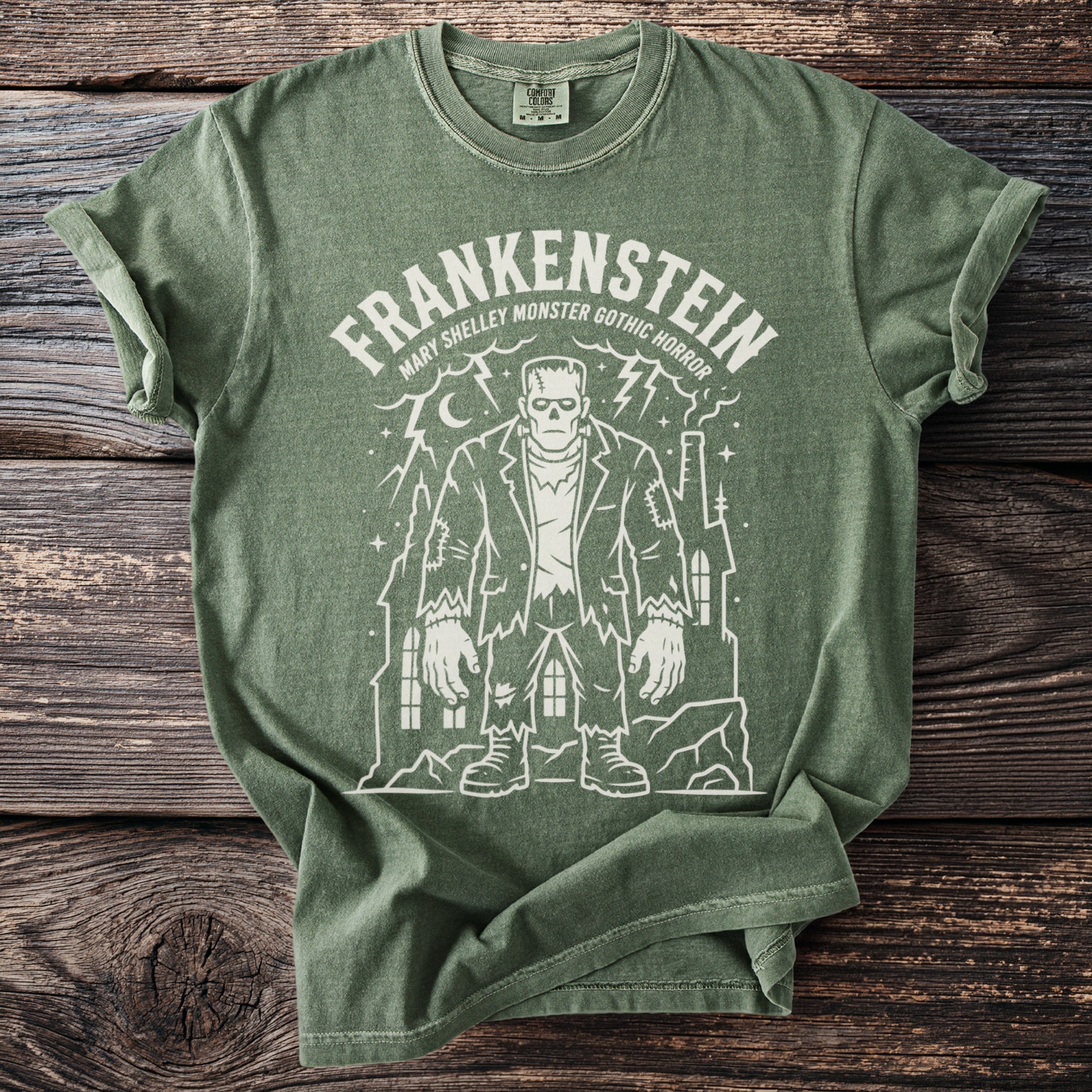 Green t-shirt with white Frankenstein monster design and text "Frankenstein Mary Shelley Monster Gothic Horror".