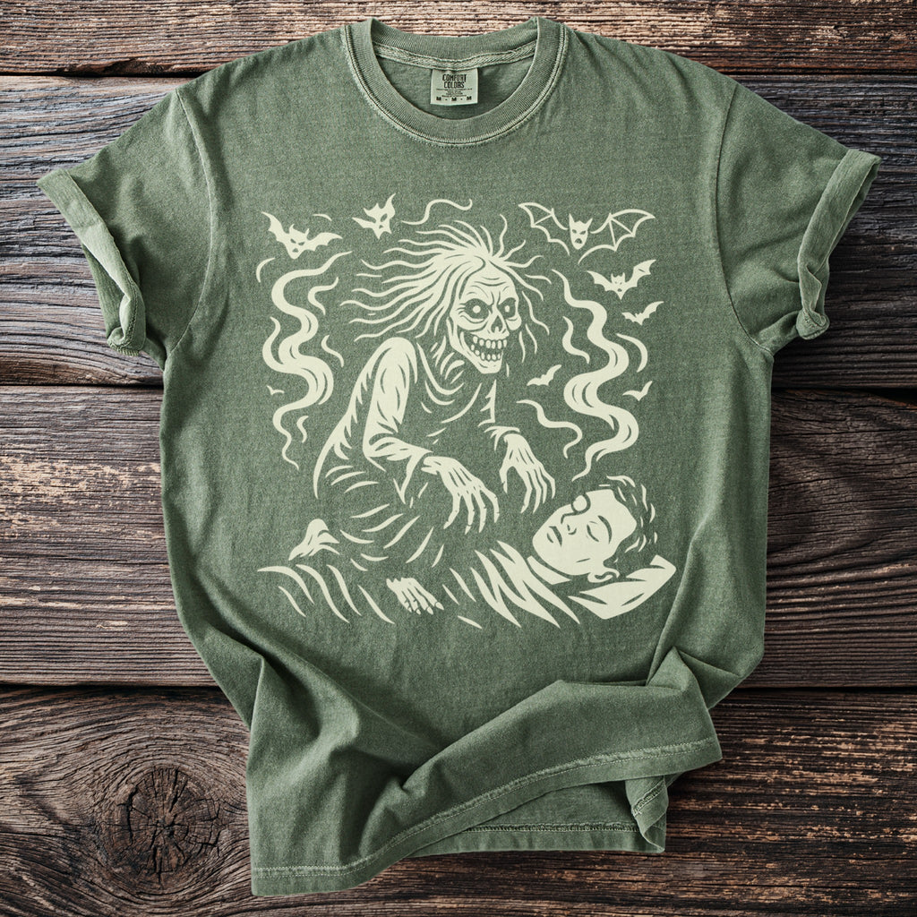 Green t-shirt with a graphic of a spooky creature over a sleeping person.