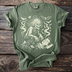 Green t-shirt with a graphic of a spooky creature over a sleeping person.