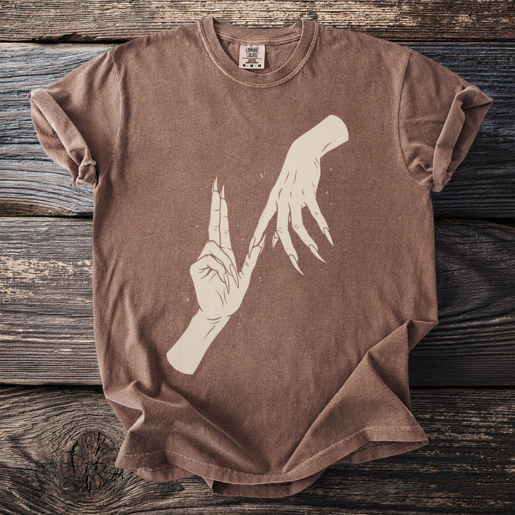 Brown t-shirt with a graphic of two hands with long, sharp fingernails.