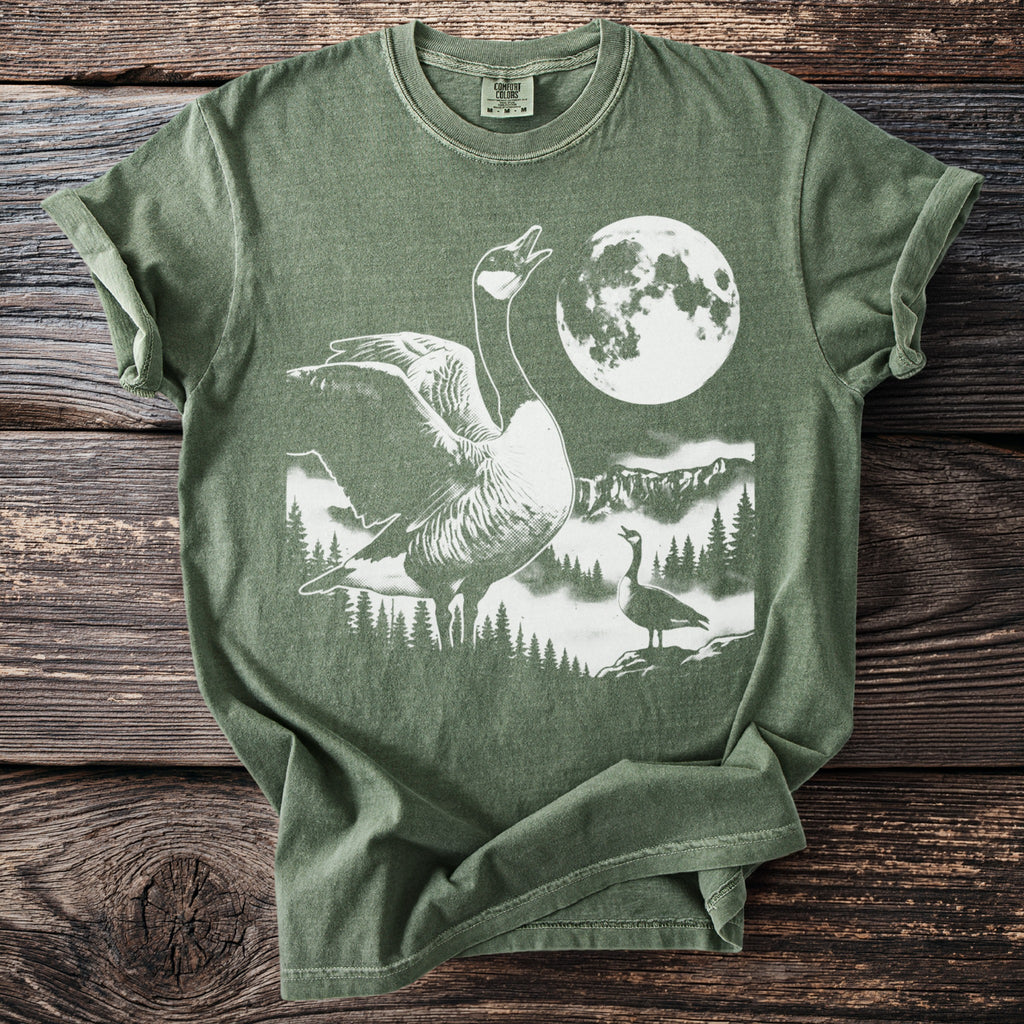 Green t-shirt with white graphic of geese, moon, mountains, and trees.