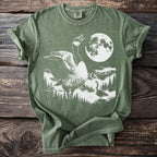 Green t-shirt with white graphic of geese, moon, mountains, and trees.