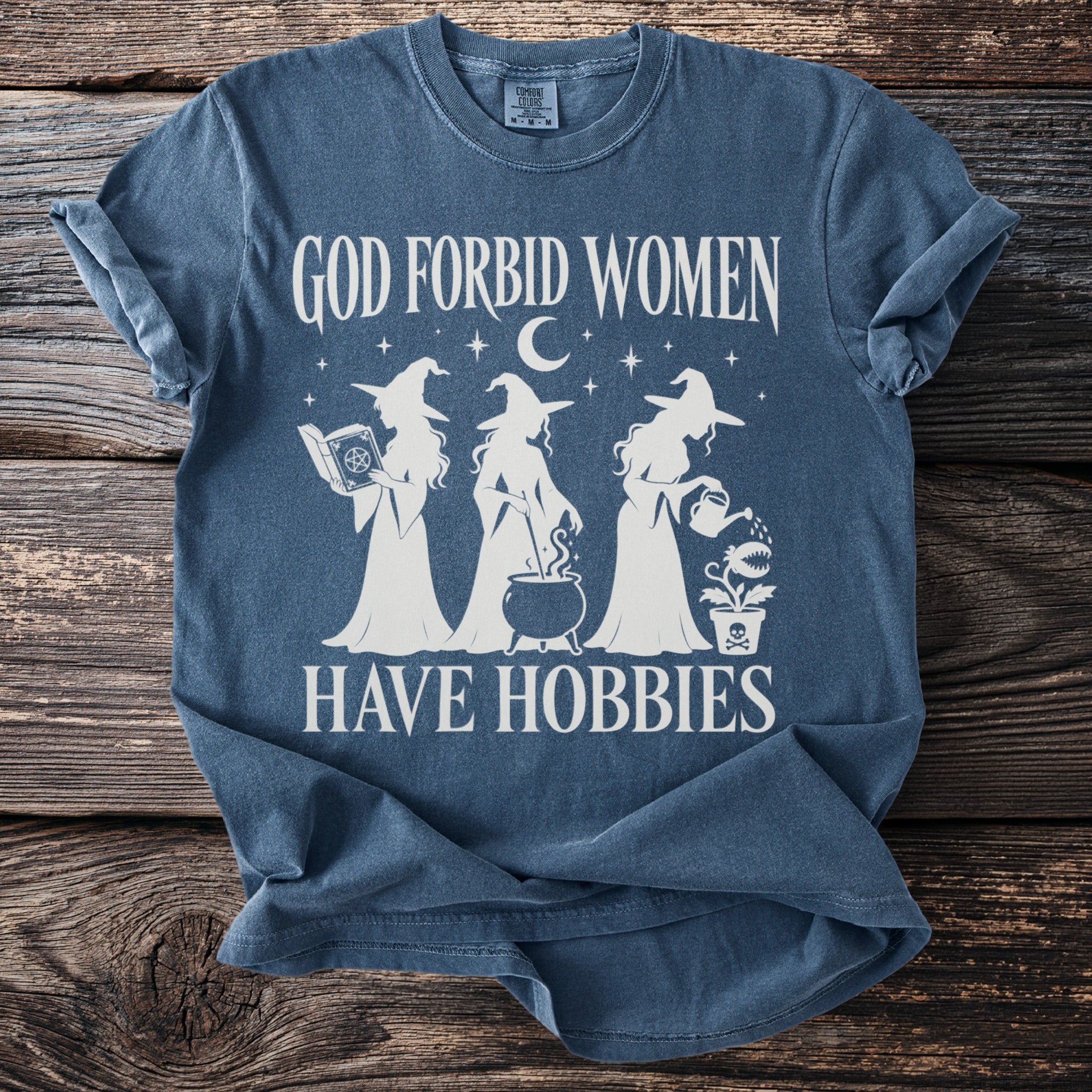 Blue t-shirt with white graphic of three witches, text "God forbid women have hobbies".