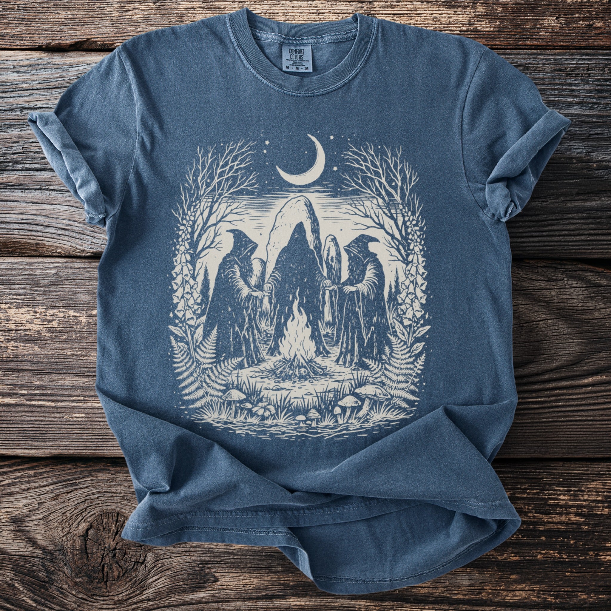 Blue t-shirt with gothic artwork of hooded figures around a campfire under a crescent moon.