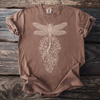 Brown t-shirt with cream-colored dragonfly and floral graphic on distressed wood.