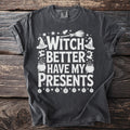 Dark gray t-shirt with white text and Halloween graphics reading "Witch Better Have My Presents".