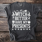 Dark gray t-shirt with white text and Halloween graphics reading "Witch Better Have My Presents".