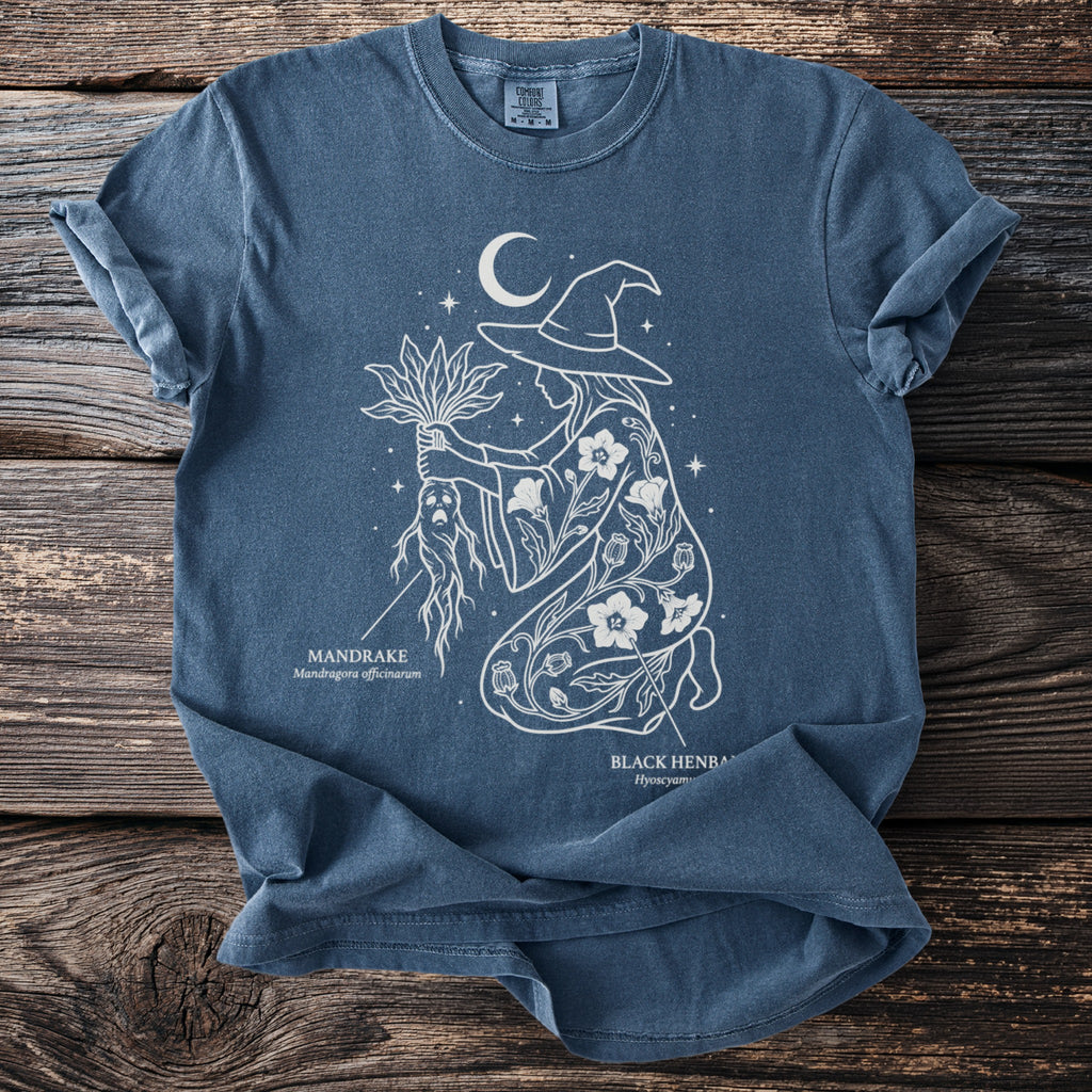 Blue t-shirt featuring a white line drawing of a witch holding a mandrake root.