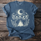 Blue t-shirt with white graphic of moon, sun, four skull figures, and campfire.