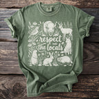 Green Comfort Colors t-shirt with white wildlife illustration and text "respect the locals."