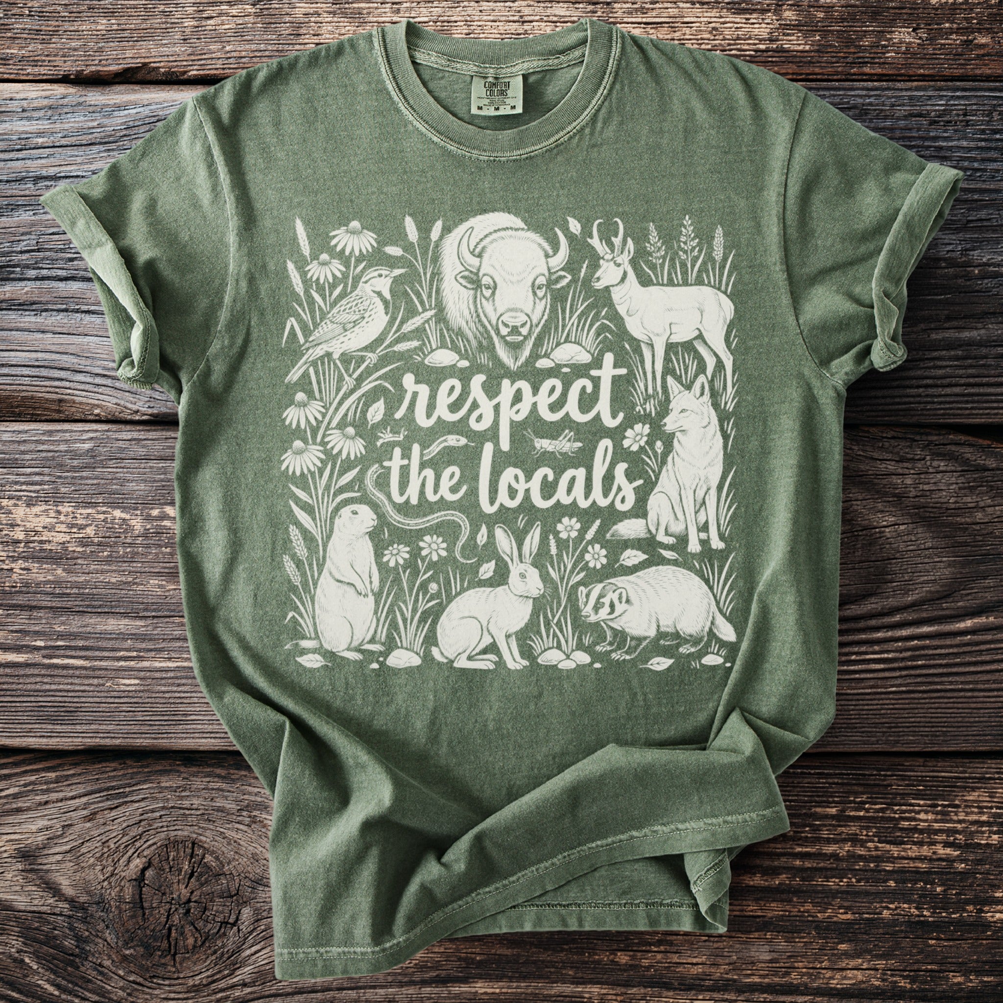 Green Comfort Colors t-shirt with white wildlife illustration and text "respect the locals."