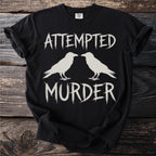 Black t-shirt with "ATTEMPTED MURDER" text and two white ravens.