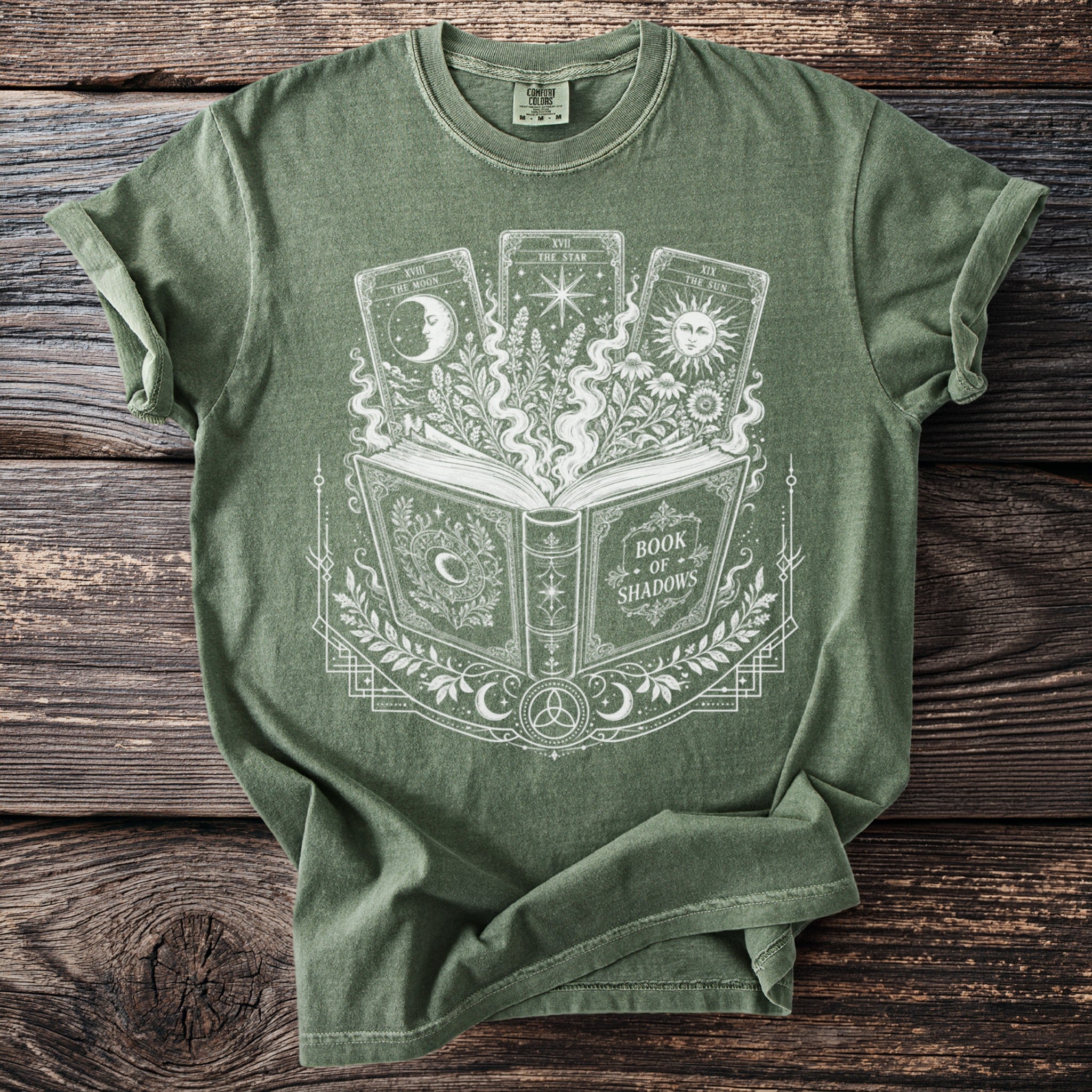 Green t-shirt with "Book of Shadows" design featuring tarot cards and foliage.