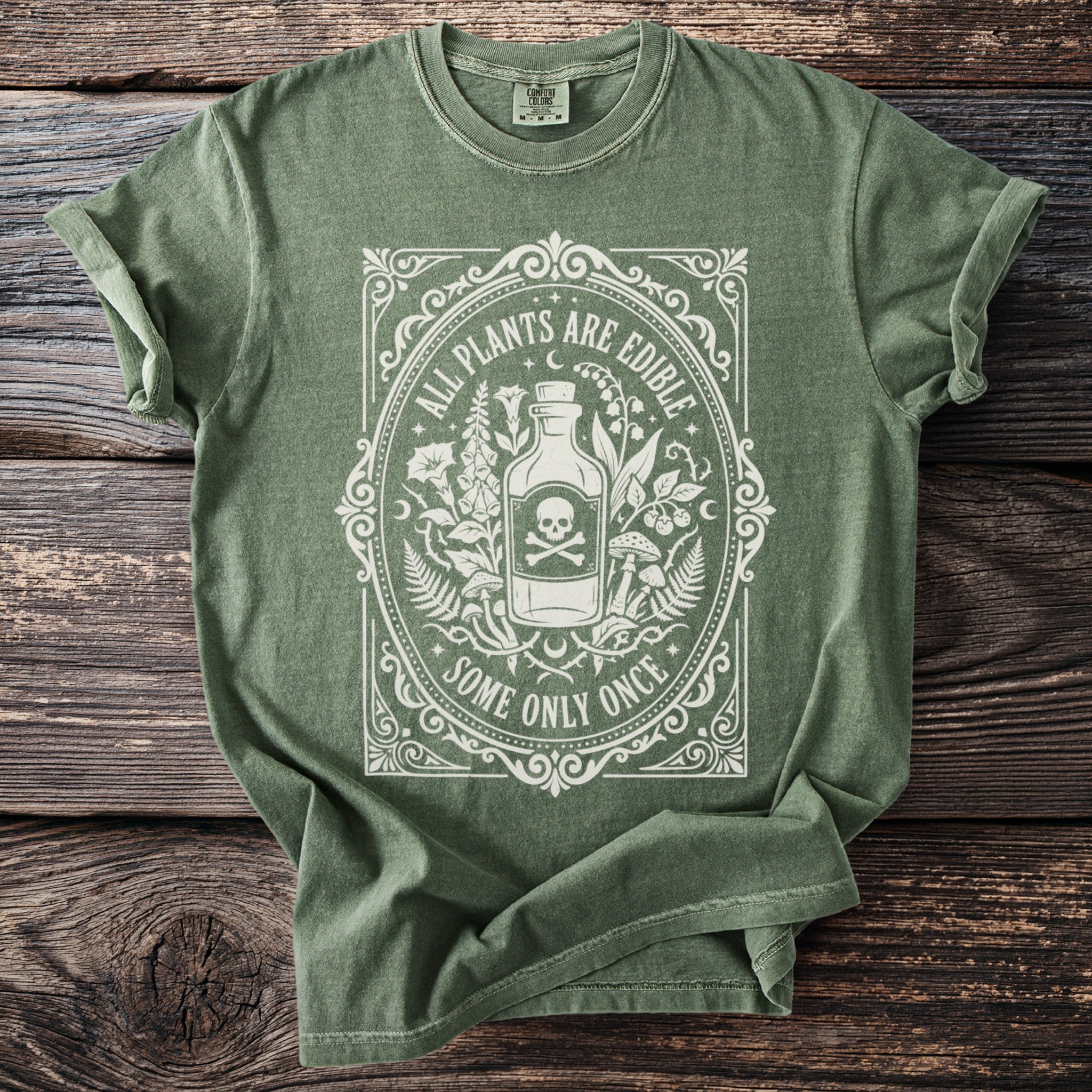 Green t-shirt with "All Plants Are Edible Some Only Once" text and skull design.