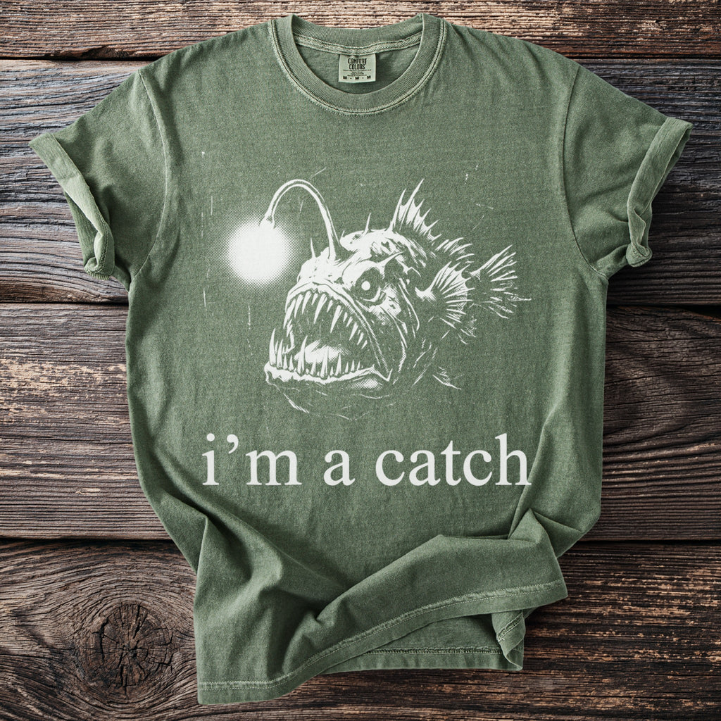 Green t-shirt with a white drawing of an anglerfish and text saying "i'm a catch."